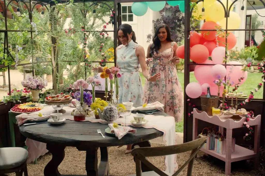 meghan markle and Mindy Kaling walking in to an orangery to an afternoon tea spread laid out on the table